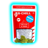Rote ‚B-CHILL‘ Packung (CBD made in Valais) mit mehrsprachigen Warntexten und davor liegenden, grünen Hanfblüten