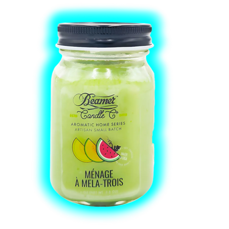 Glas mit grünlicher Kerze, schwarzem Schraubdeckel, Logo der Beamer Candle Co und Fruchtabbildungen auf dem Etikett