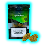 Zwei getrocknete Hanfblüten vor der ‚Lemongrass Haze‘-Verpackung. Sichtbar: Preis 9.90 CHF und mehrsprachige Gesundheitstexte.