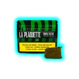Vorderseite einer Verpackung mit der Aufschrift 'LA PLAQUETTE TRIPLE FILTRÉ 3.5G' und einem Stück CBD Hasch davor