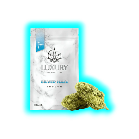 Verpackung mit Marmoroptik und Aufschrift 'LUXURY THE FINEST CBD SILVER HAZE INDOOR 30g/40.-' neben zwei Cannabisblüten